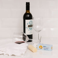 WOW Stick stain remover next to a bottle of wine and 2 glasses